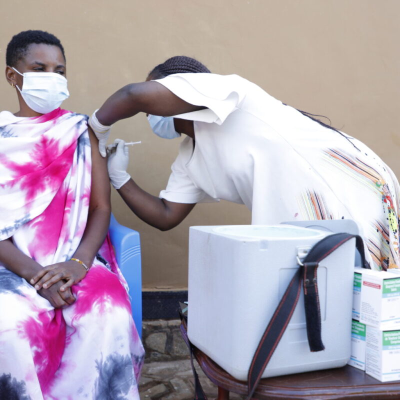 A woman receives an injection in her arm from a nurse.