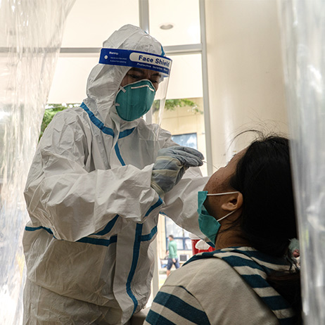 A healthcare worker in protective gear testing a patient.